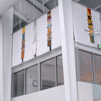 Totems For Maynard Washington Park Natatorium, Installation Atlanta, GA-Multiple totems that are multi-colored hanging on a wall close the ceiling in a Natatorium.