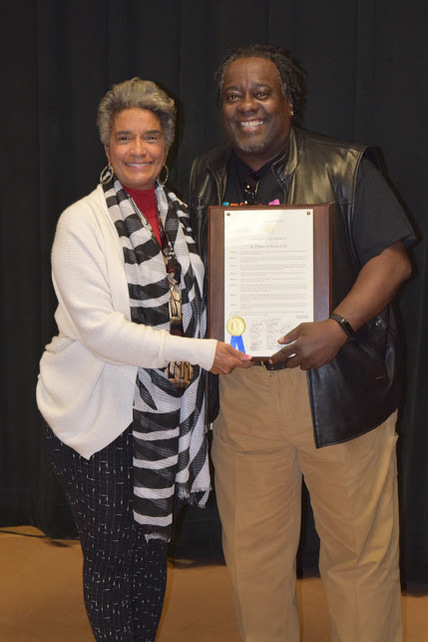 Proclamation from The City Of Atlanta- A Man and A Woman Posing for a Photo in Causal Wear. The Man on the Right is Holding a Sheet of Paper.