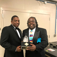 Arkansas Black Hall of Fame- Two Men in Tuxedos Posing For a Photo Holding a Award Trophy.