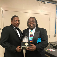 Arkansas Black Hall of Fame- Two Men in Tuxedos Posing For a Photo Holding a Award Trophy.