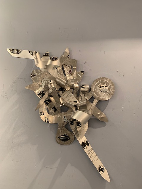 A Prayer Before-Abstract Art Piece With Various Shapes that Resembles Ties. The Ties are Bent in Various Ways. The Piece is Silver.