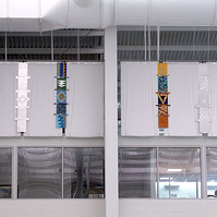 Totems For Maynard Washington Park Natatorium, Installation Atlanta, GA-Multiple totems that are multi-colored hanging on a wall close the ceiling in a Natatorium.