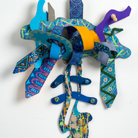 Faith N Determination-Multicolored Abstract Art Piece Hung on A Wall With Various Shapes that Resembles Ties. The Ties are Bent in Various Ways. 
