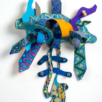 Faith N Determination-Multicolored Abstract Art Piece Hung on A Wall With Various Shapes that Resembles Ties. The Ties are Bent in Various Ways. 