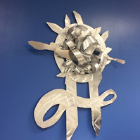 When Promise-Abstract Art Piece With Various Shapes that Resembles Ties. The Ties are Bent in Various Ways. The Piece is Silver.