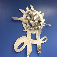When Promise-Abstract Art Piece With Various Shapes that Resembles Ties. The Ties are Bent in Various Ways. The Piece is Silver.