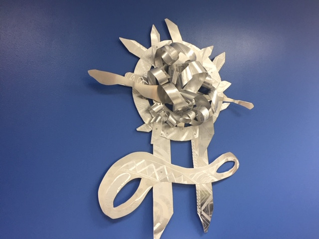 When Promise-Abstract Art Piece With Various Shapes that Resembles Ties. The Ties are Bent in Various Ways. The Piece is Silver.