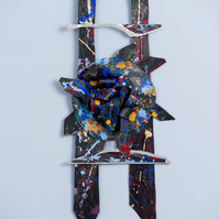 Midnite Prayers-Abstract cutout art piece on paper that resembles ladder  which has a circle in the middle. The colors of the piece are mostly black with multicolor splatters.