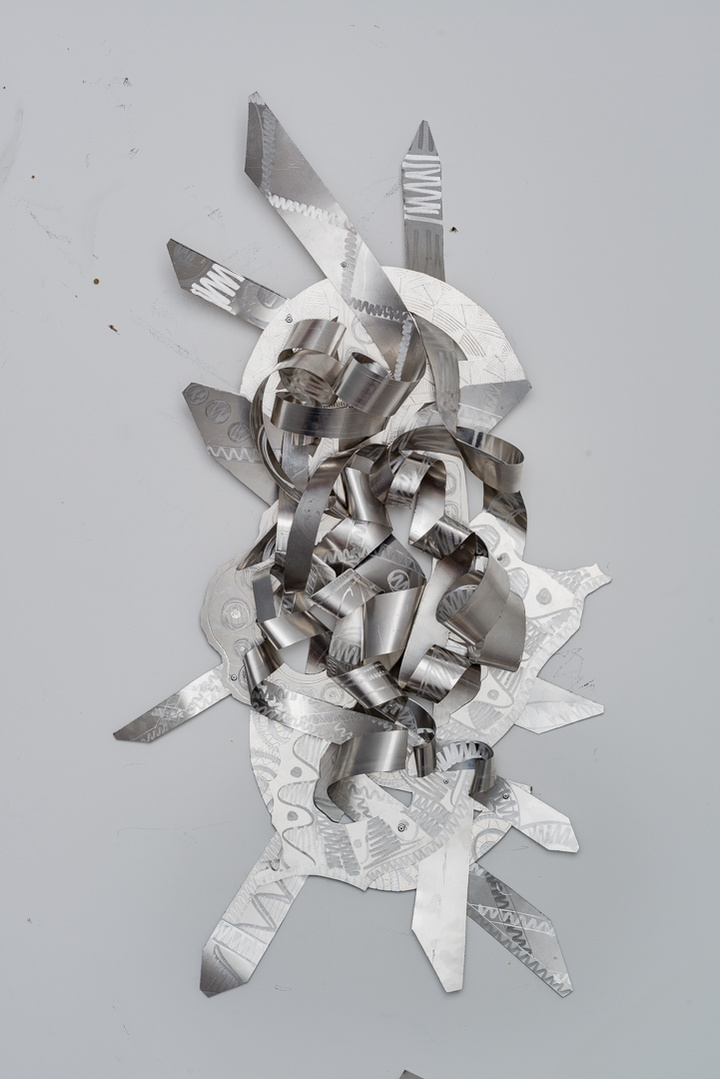 A Tale of Two-Abstract Art Piece Hung on A Wall With Various Shapes that Resembles Ties. The Ties are Bent in Various Ways. The Piece is Silver. 