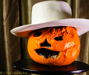 A weathered pumpkin sports a white hat.