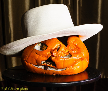 The same collapsed pumpkin wearing a white, rather formal hat.