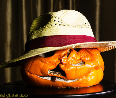 a collapsed pumpkin sporting a summery straw hat.