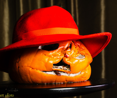 A collapsed pumpkin wearing a red felt hat.