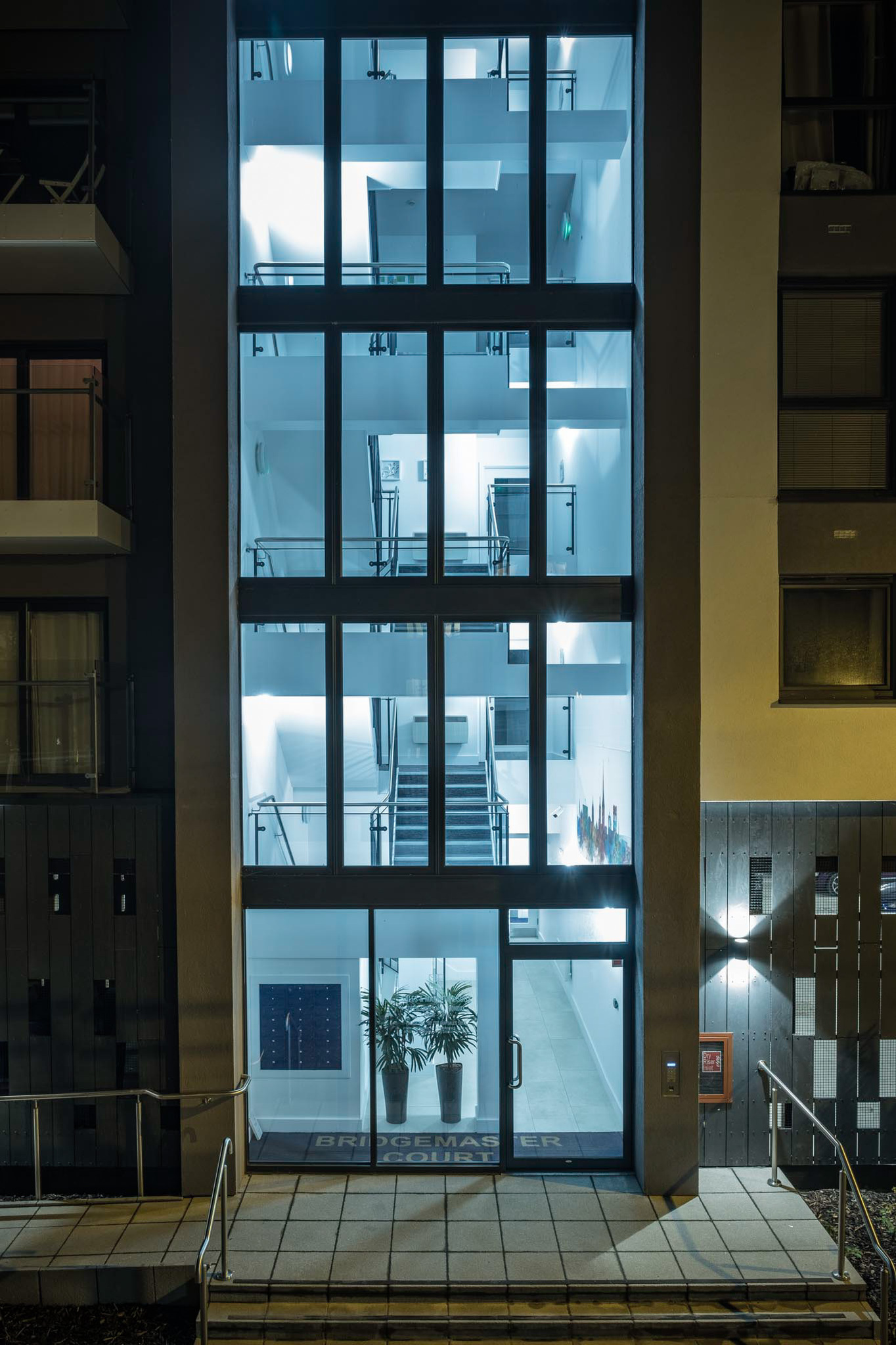 Novi sad tall glass Entrance and stairwell for Flats on the riverside of Norwich illuminated at night