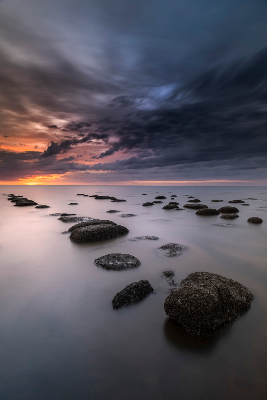 Sunset over the rocks of Hunstanton with the sea smoothed out with a long exposure
