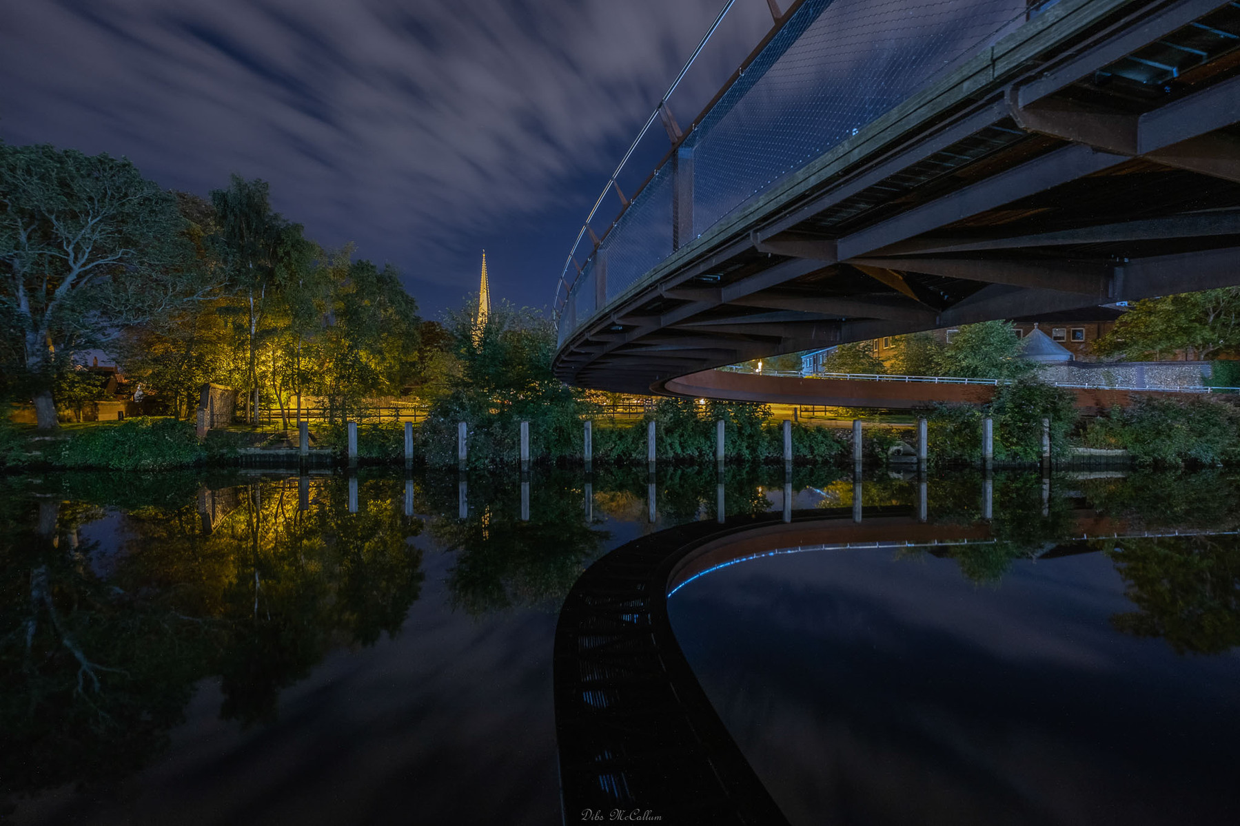 The stunning Jarold bridge in Norwich Norfolk that spans over the River wensum, made of metal and left bear it takes on a rusty colour.You can see the Norwich cathedral in the distance of this night image