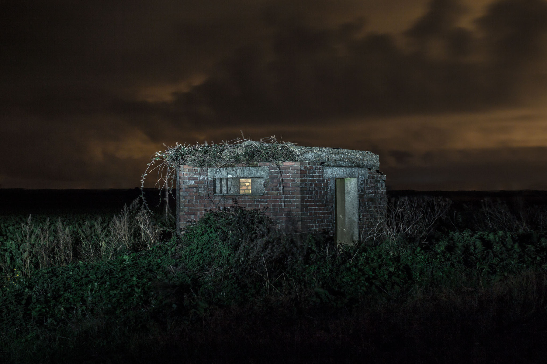 WW2 pillbox protecting a gun battery on the cliff edge at night illuminated with flash lighting.