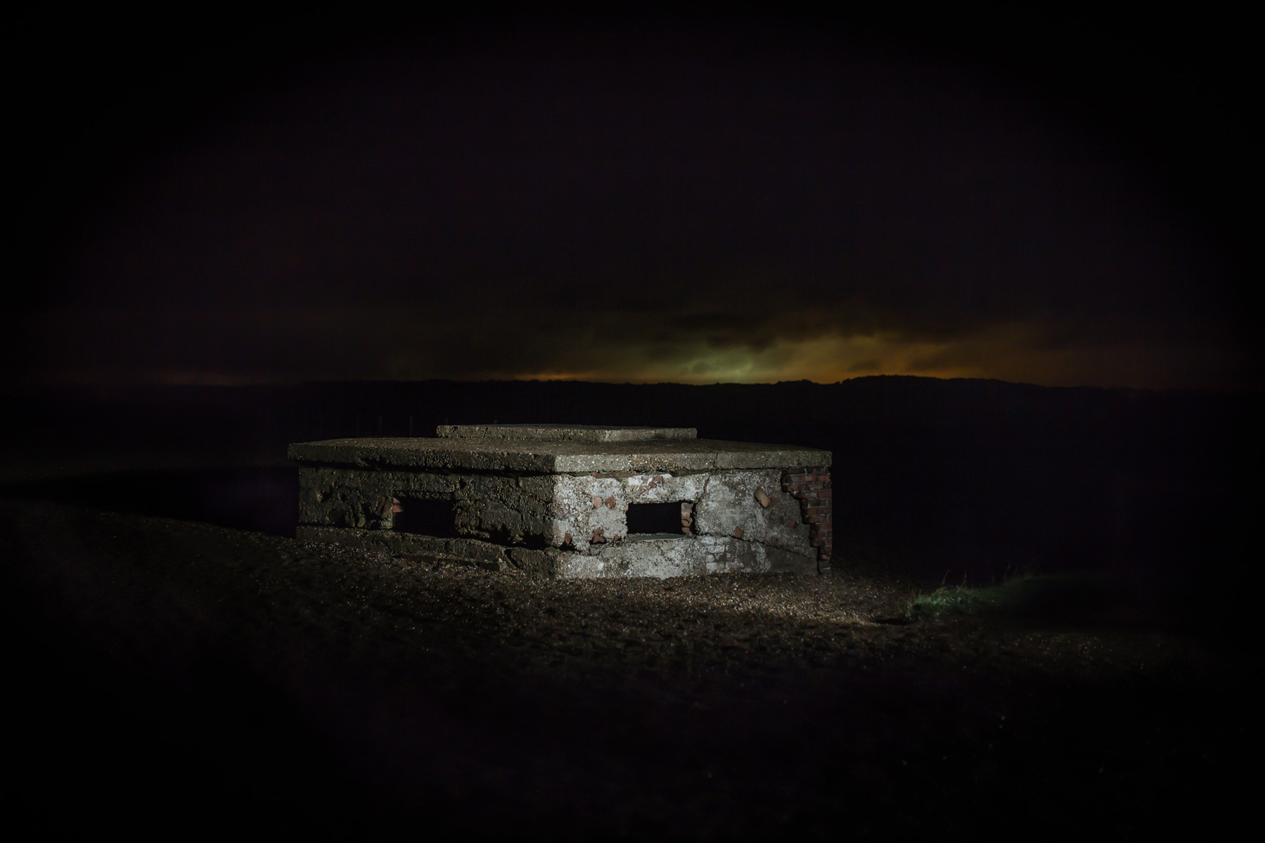 WW2 BUNKER pillbox on a shingle beach at night illuminated with flash lighting.