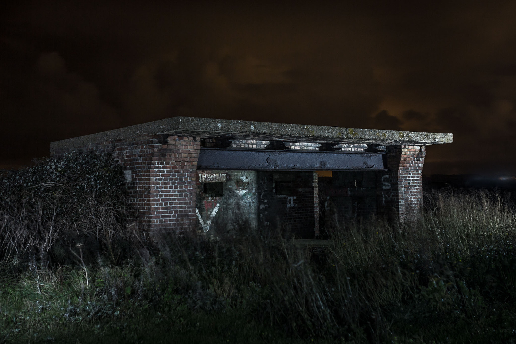 WW2 gun battery on the cliff edge at night illuminated with flash lighting.