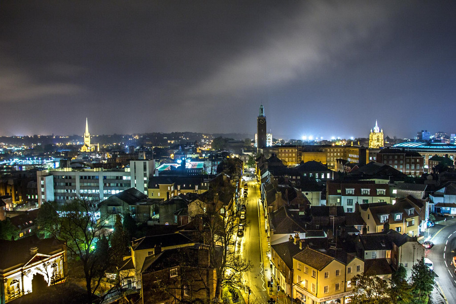 The skyline of Norwich city centre shows the city hall clock tower and Norwich cathedral taken from up hight from the church on st Giles street at night