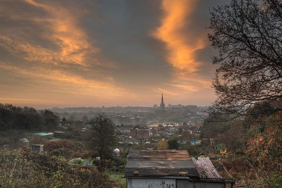 Cityview of Norwich city with the cathedral and allotments with a red sky and white clouds at sunrise on a cold morning