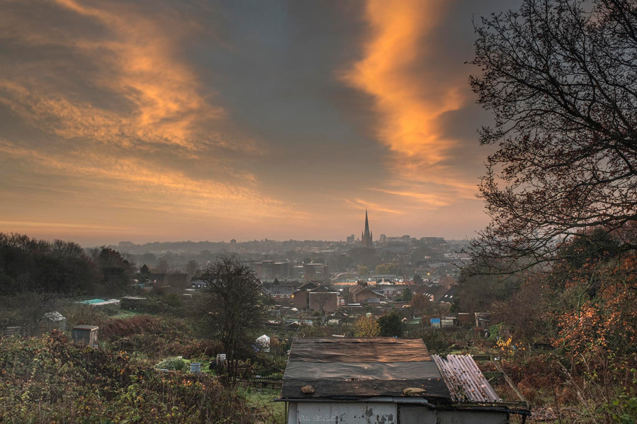 Cityview of Norwich city with the cathedral and allotments with a red sky and white clouds at sunrise on a cold morning