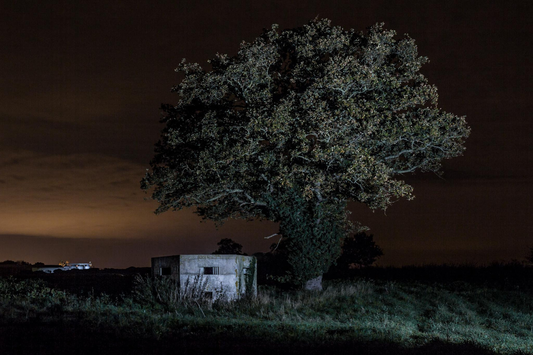WW2 pillbox middle of a field at night illuminated with flash lighting.