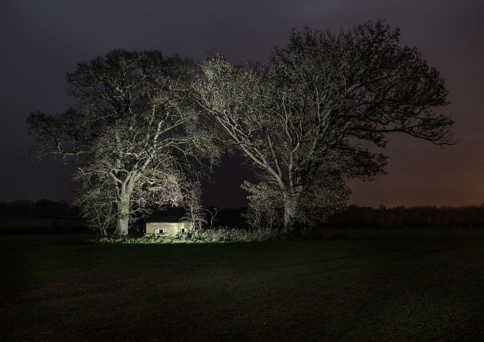 WW2 BUNKER pillbox middle of a field at night illuminated with flash lighting.