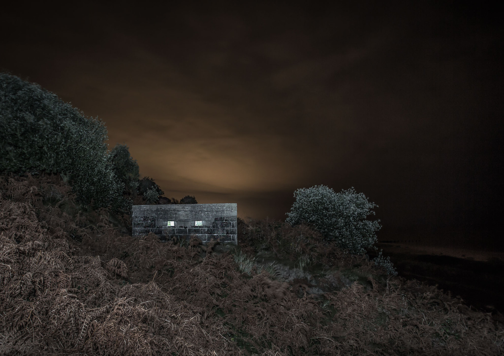 WW2 BUNKER pillbox on the cliff edge at night illuminated with flash lighting.