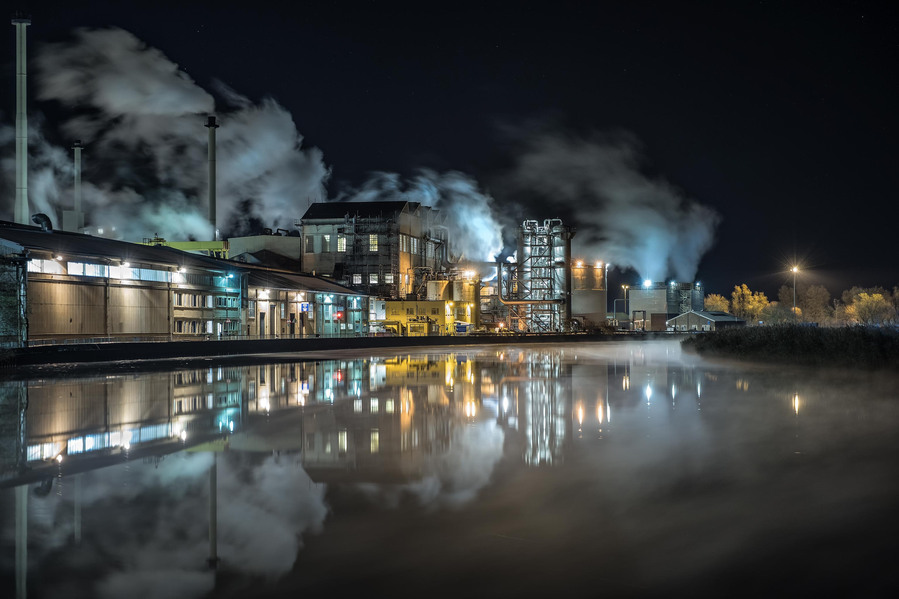 Cantley sugarbeet factory in Norfolk at night with steam billowing out of the chimneys and from the buildings on the site as mist rolls down the river and the lights of the site reflect perfectly onto the calm river