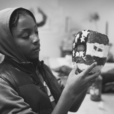 a black and white image of a boy holding a mask painted like the American flag