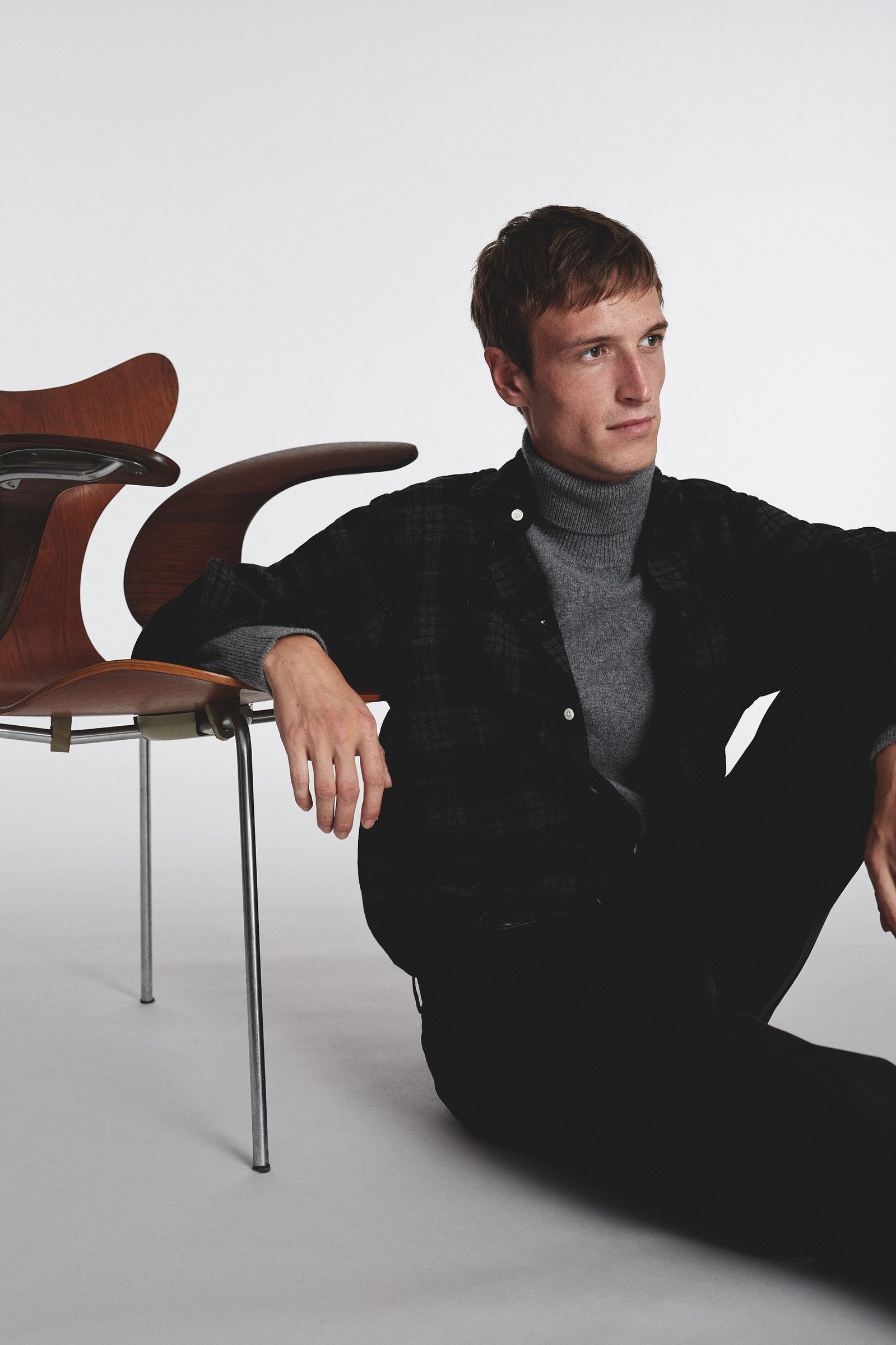 Immerse yourself in the epitome of style with our captivating fashion image featuring a debonair man seated gracefully by a chic chair. The scene unfolds with a carefully curated ensemble, showcasing the perfect fusion of comfort and sophistication.