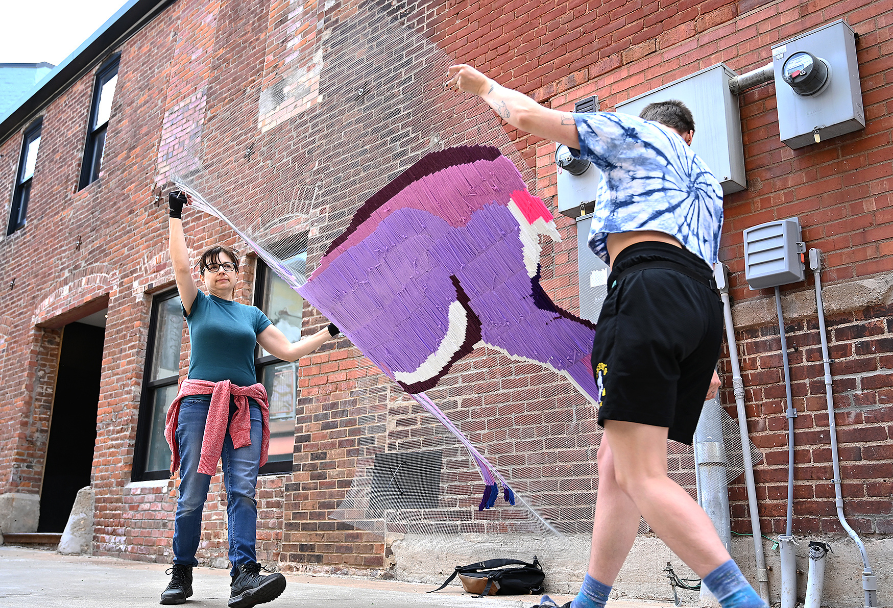 <p>Sarah Nguyen, left, helps carry a section of Mary Sandbothe’s Deer Run with Maggie Adams, right, on Tuesday, Feb. 27, 2024, in Alley A in Columbia. Four unique sections make up the art installation.</p>