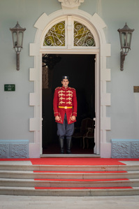 A guard in formal attire stands at the entrance to the Blue Palace in Cetinje, Montenegro.