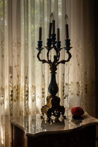 Ornate candelabra silhouetted against a lace curtain in a window
