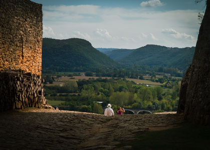 Two people sitting on a ledge high above a valley in the Dordogne, France