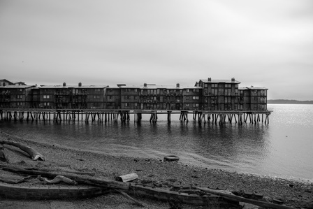 Black and white image of a building built on a pier out into a bay.