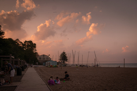 Pink sunset at the beach with children playing in the sand.