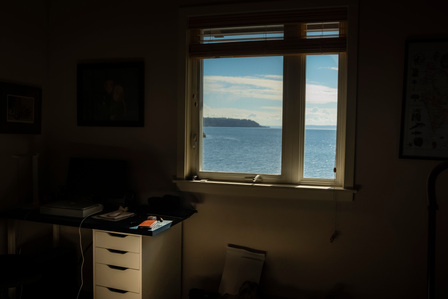 Small dark office with a window to the seashore