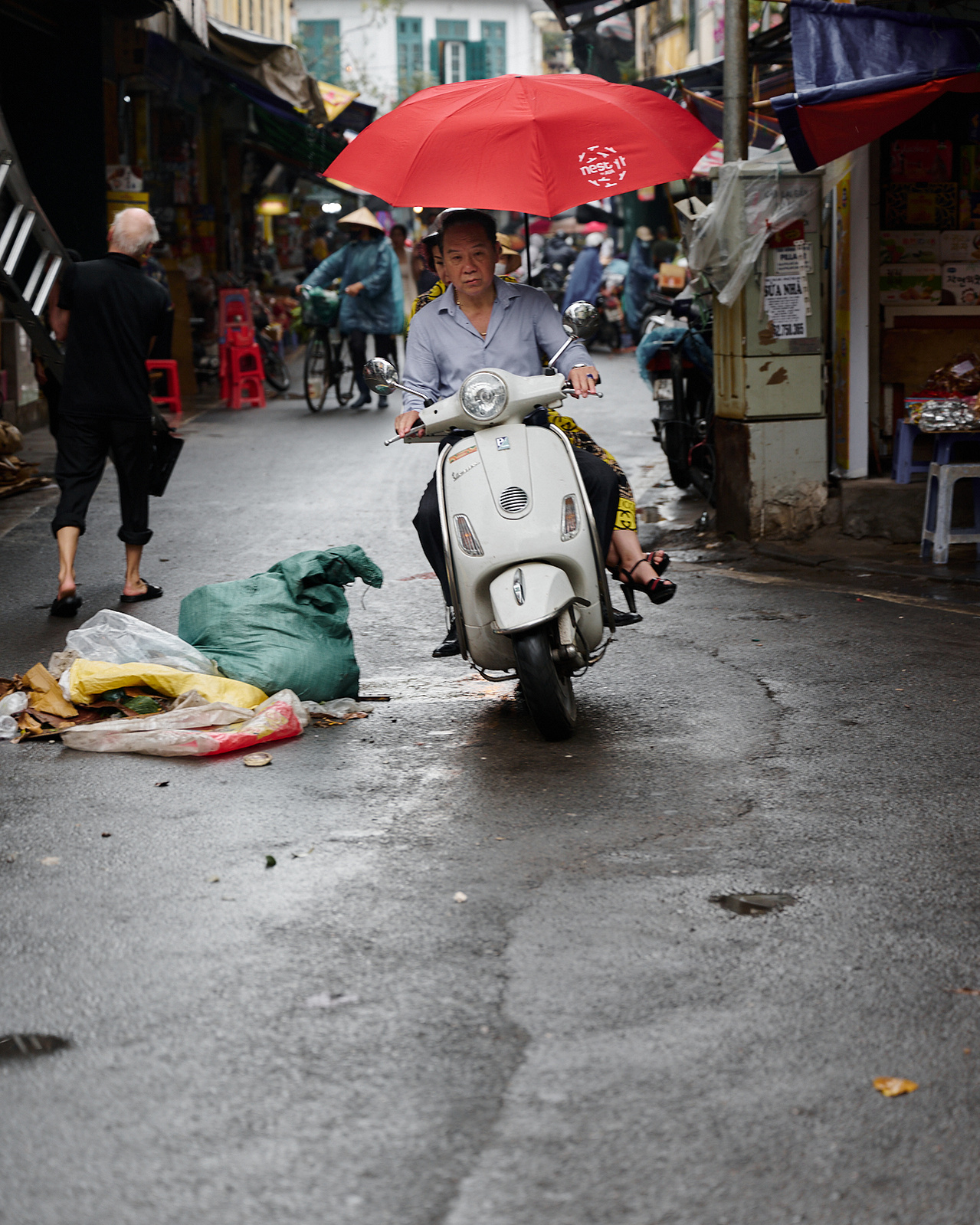 Life in Hanoi is on the streets and avoiding some of it is a necessity even on a scooter in the rain