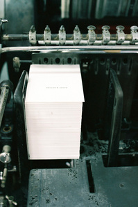 A stack of name cards being printed using a letterpress machine.