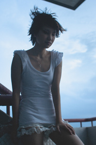 Portrait of a tall girl in a white dress looking troubled.