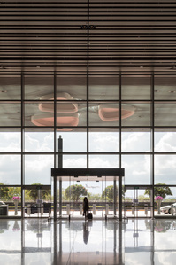 A lady with a suitcase enters Changi Airport T4 designed by SAA Architects and constructed by Takenaka Corporation.