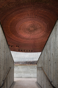 The copper circular roof of Temppeliaukio Church designed by Timo & Tuomo Suomalainen, as viewed from the off-form concrete corridor walls.