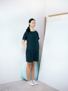 Portrait of a model wearing a Muji linen top standing in front of a big mirror. The photograph is shot using analog film.