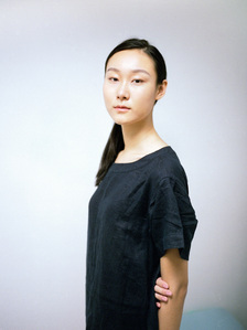 Portrait of a model wearing a Muji linen top folding her arms. The photograph is shot using analog film.