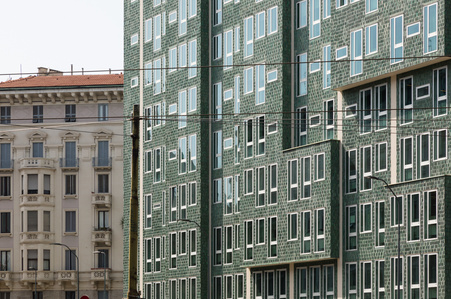 The juxtaposition of the modern green-tiled facade of the Montedoria Building in Milan, designed by Gio Ponti, with the surrounding building.