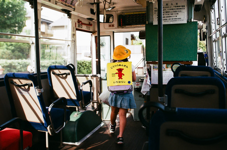 Japanese schoolgirl carrying a Japanese schoolbag alighting from a bus.