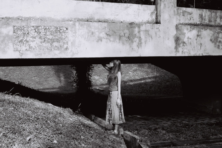 Portrait of a girl under a bridge. The photograph is shot using black and white analog film.