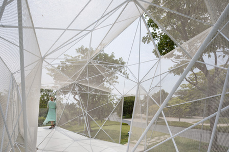 A woman looking out to the landscape from inside of the Airmesh designed by Airlab.